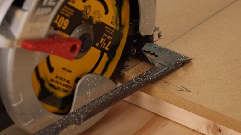 A circular saw blade being aligned with the edge of an MDF board.