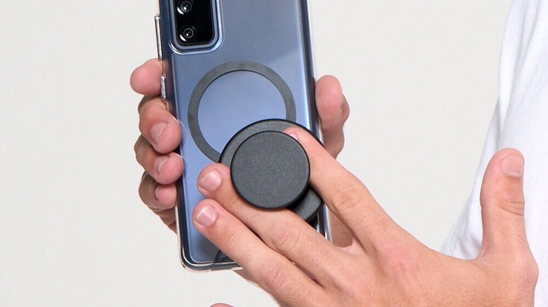 Close-up of a hand comfortably holding a large Android smartphone using a PopSockets MagSafe Grip.