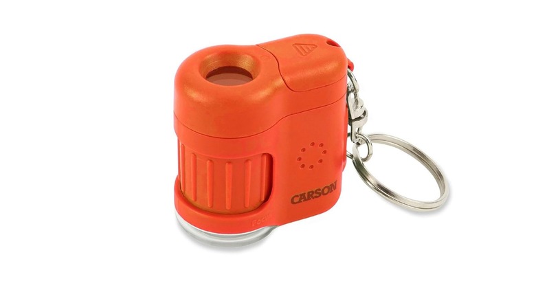 An orange Carson MicroMini microscope with a keychain clip and adjustable optical lens.