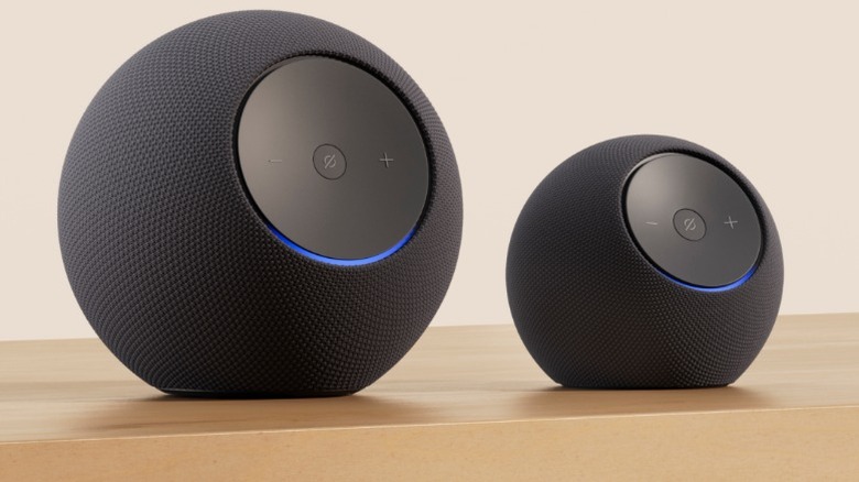 An Amazon Echo Dot Max sitting next to an Echo Studio on a wooden table.