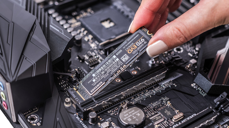 A person plugging a Samsung 970 EVO SSD into an M.2 slot on a computer motherboard.