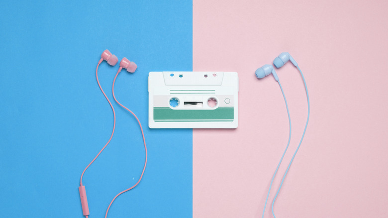 Pink and blue wired headphones centered around a retro cassette tape on a split-color background.