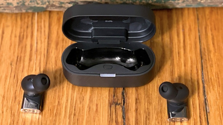 A person using a smartphone while wearing the Status Pro X earbuds.