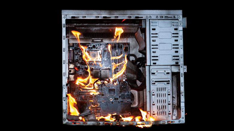 A desktop computer tower with flames and smoke coming from the internal components.