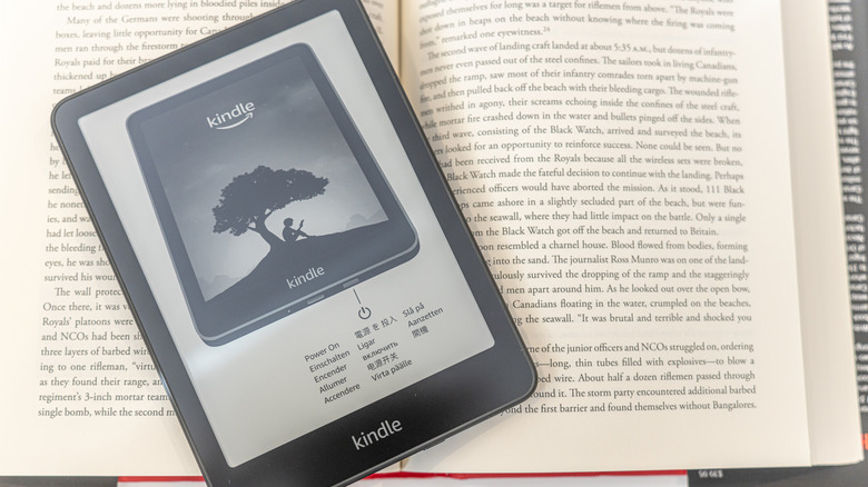 A Kindle Paperwhite 12th Gen resting on a physical book showing high-contrast text.