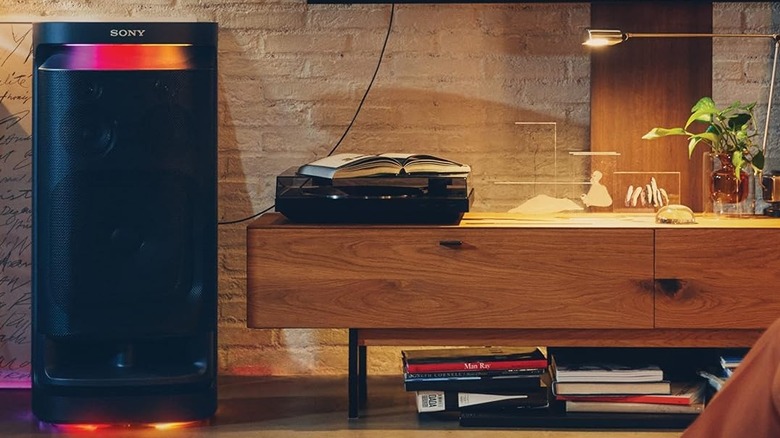 The Sony SRS-XV900 set up in a living room next to a wall-mounted TV, connected via optical cable.