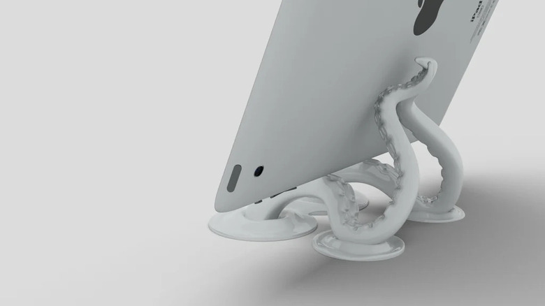 An iPad propped up on a creative 3D printed stand shaped like octopus tentacles.