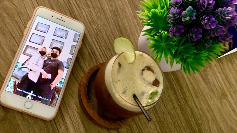 A white iPhone 8 on a table surface near decorative items.
