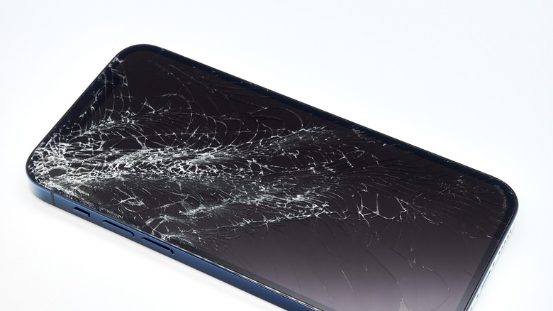 A blue iPhone 12 with a severely cracked screen display.