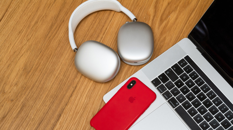 AirPods Max 2 shown next to an iPhone and a MacBook on a desk.