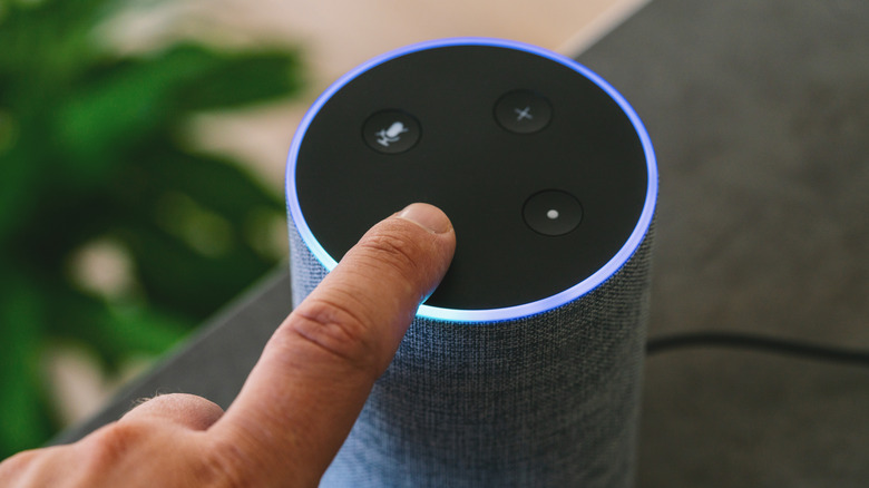 A close-up of a user interacting with an Amazon Echo Plus showing a bright blue and cyan LED status light.