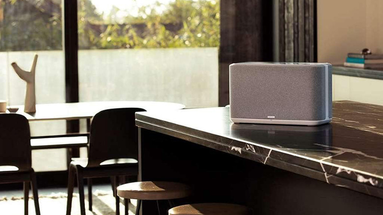 A Denon Home 350 speaker placed on a kitchen counter near a window.