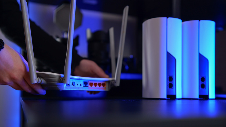 A person setting up modern mesh Wi-Fi nodes on a tabletop to create a unified home network.