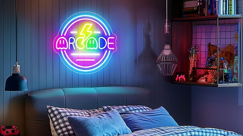 A blue and pink neon 'Gamer Arcade' sign mounted on a wall above a bed, casting a colorful glow.