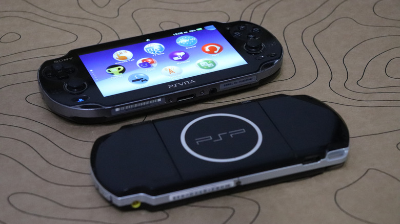 Comparison shot of a PS Vita and a PSP handheld console.