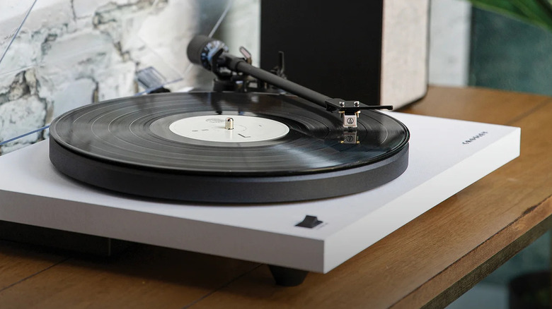 A white entry-level suitcase-style turntable playing a vinyl record.