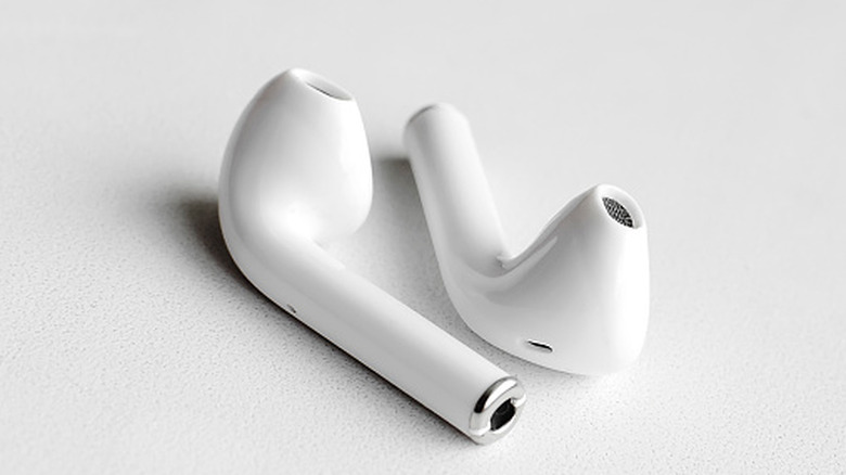 A pair of white wireless earbuds displayed clearly to show maintenance points.