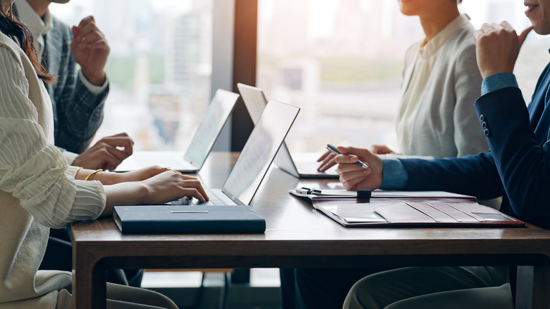 A diverse group of professionals using high-end laptops during a business meeting.