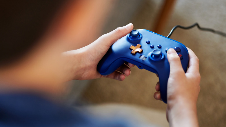 A blue gaming controller held by a user.