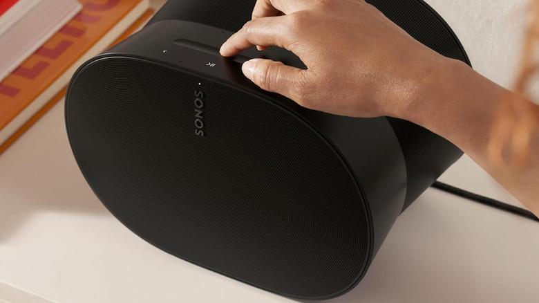 A close-up of a person's hand adjusting the controls on a white Sonos Era 300 speaker.