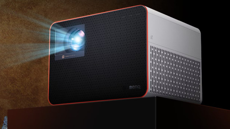 A BenQ gaming projector mounted on a bracket, showing its large cooling vents and lens.