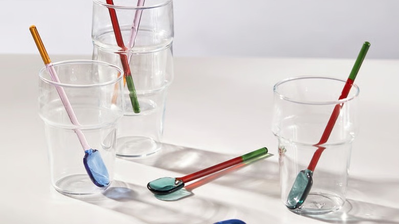 Several multicolored Fengomarre glass spoons resting inside a clear glass container.