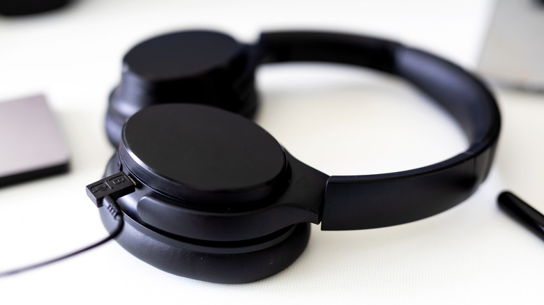 A pair of wireless headphones charging via a USB cable.