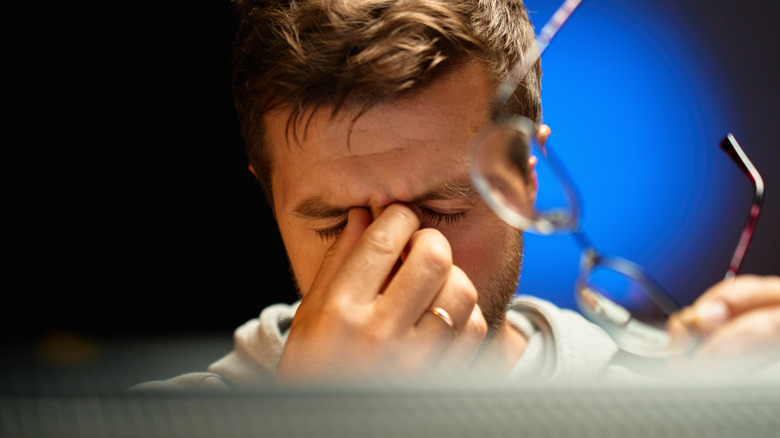 A man rubbing his tired eyes in a state of exhaustion or stress.