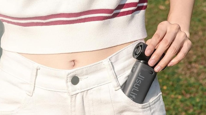 A person sliding a compact Jisulife Life9 fan into their pants pocket.