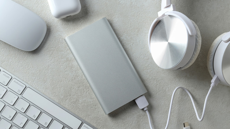 Wireless headphones connected to a portable power bank during charging.