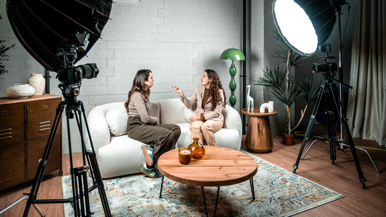 Two people recording a podcast in a professional studio setup with microphones and lighting.