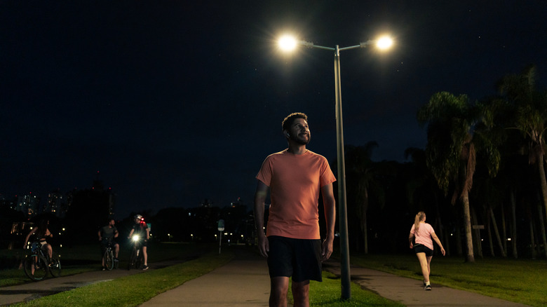 A group of people standing and talking under a streetlight in a dark public park or street.